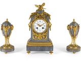 une horloge et deux vases posés sur une surface blanche