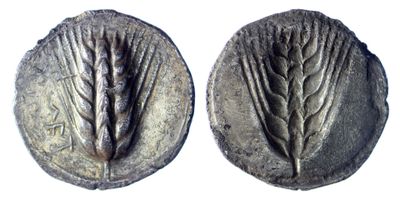 a close up of two silver coins with leaves on them