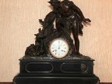 une statue représentant un homme avec un chien et une horloge posée sur une table