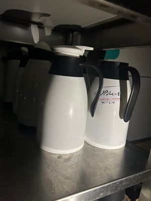 two white and black coffee pots sitting on a shelf