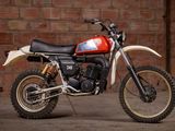 a red and white dirt bike parked in front of a brick wall
