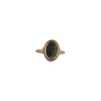 Gros plan sur une bague en or ornée d'une pierre verte
