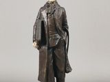 figurine représentant un homme en manteau et chapeau, debout sur un rocher