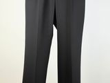 black pants hanging on a wooden hanger against a white wall