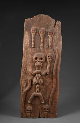 une plaque sculptée représentant un squelette tenant une tête humaine