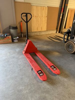un chariot élévateur dans un garage, avec une palette au premier plan