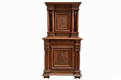 une grande armoire en bois dont la façade est ornée de sculptures