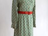 une robe verte et blanche avec une ceinture rouge sur un mannequin