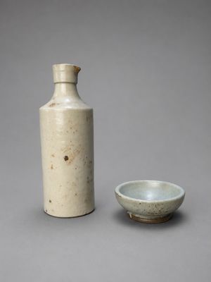 une image représentant un vase blanc et un petit bol posés sur une surface grise
