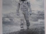 affiche représentant un homme en combinaison spatiale debout devant une montagne