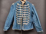une vieille veste militaire bleue avec des boutons blancs, suspendue à un cintre