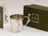 une tasse en argent posée à côté d'une boîte de thé