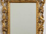 un miroir doré richement décoré accroché au mur, à côté d'un mur blanc