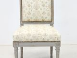 a white chair with a floral upholstered back and wooden legs