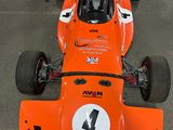 an orange race car that is parked in a lot