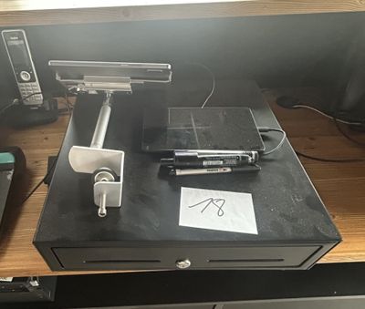 an image of a cash register on a desk with a pen and a cell phone