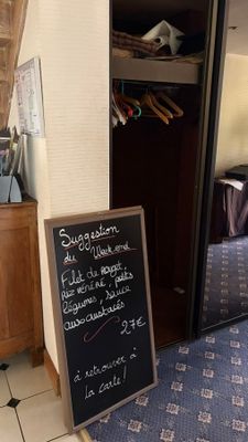 a blackboard sign in the corner of a room next to a bed