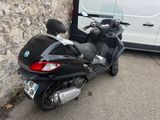 a scooter parked next to a van on the side of the road