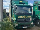 two green trucks parked next to each other on the side of the road