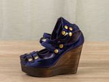 navy blue leather wedge sandals with gold studs on a wooden platform