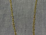 un collier à chaîne en or posé sur un tissu gris
