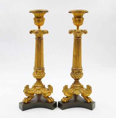 paire de bougeoirs anciens en laiton reposant sur des socles en marbre noir