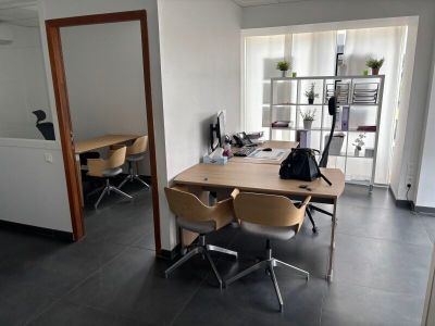 une pièce avec un bureau, des chaises et un ordinateur portable posé dessus
