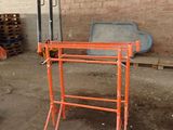 orange scaffolding stands in a warehouse with pallets of wood in the background