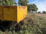 a yellow dumpster sitting in the middle of a field