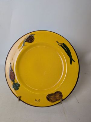 une assiette jaune ornée d'un motif, posée sur une surface blanche