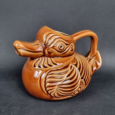 un canard en céramique marron posé sur une surface noire
