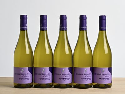 four bottles of white wine are lined up on a wooden table