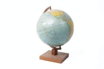 un petit globe posé sur un socle en bois, lui-même posé sur une surface blanche
