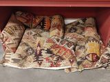 a red cabinet with a bunch of rugs on it