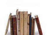 several old books are stacked on top of each other on a white surface