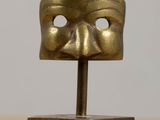 an image of a bronze mask on a stand on a wooden table