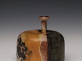 une image représentant un vase marron et noir posé sur une surface blanche