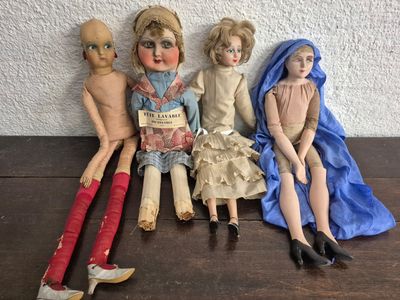 trois poupées assises sur une table, avec un livre devant elles