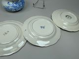 three plates on the table with a vase in the background