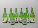 six bouteilles de vin vert alignées sur une table