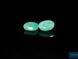 a pair of green jade beads on a black surface
