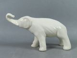 une figurine d'éléphant blanc posée sur une surface grise