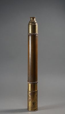une vieille pipe en laiton munie d'un embout métallique, sur fond gris