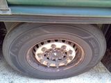 a dirty tire on the back of a green pick up truck