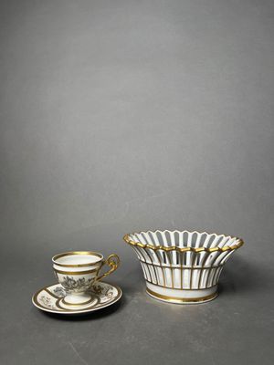 a white and gold cup and saucer with a saucer on the side