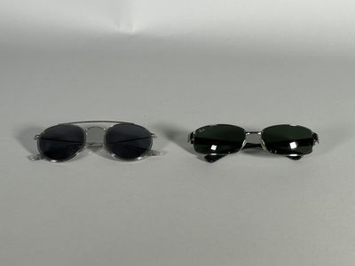 two pairs of sunglasses sitting next to each other on a white surface