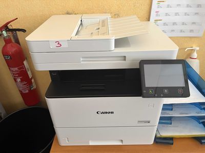 a canon printer sitting on a desk next to a fire extinguisor