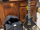 a guitar and amp sitting on the floor next to a cabinet