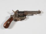 un vieux revolver avec une poignée en bois sur une surface blanche