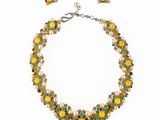 un gros plan d'un ensemble composé d'un collier et de boucles d'oreilles sur fond blanc